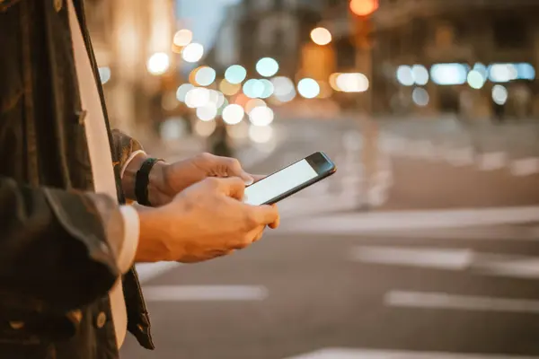 Açık havada, Night City Caddesi 'nde akıllı telefonları olan erkeklerin yakın çekimleri.