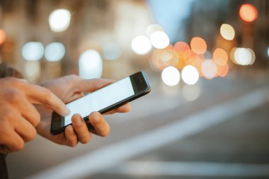 Açık havada, Night City Caddesi 'nde akıllı telefonları olan erkeklerin yakın çekimleri.