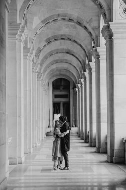 Aşık bir çift Paris sokaklarında yürüyor, ceketli ve takım elbiseli bir adam, bereli bir kız ve sonbaharda siyah beyaz bir trençkot giymiş bir kız.