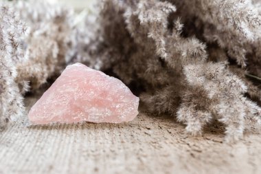 Ahşap arka planda gül kuvars mineral numunesi. Gül kuvars iyileştirici bir pembe taştır. Sevgiyi yansıtır ve duyguları teşvik eder.