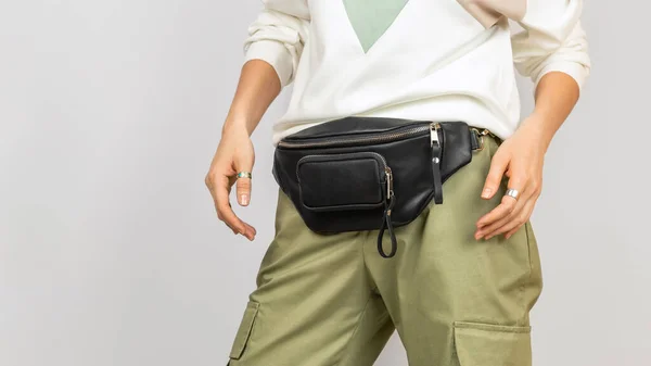 Black Leather Waist Bag on a Woman Wearing Green Trousers and Sweatshot. Handmade Leather Accessories Goods