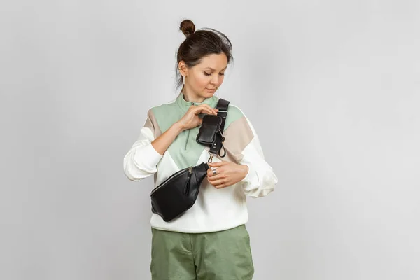 女性を身に着けている黒革ウエストバッグ付き取り外し可能なコイン財布アクセサリー用収納キー シガレットまたはイヤフォンストラップ スタジオショットに添付 ストックフォト