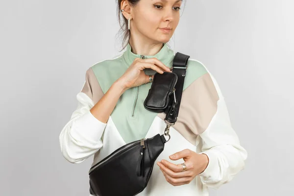 Genuine Leather Waist Bag with Removable Coin Purse Accessory for Storing Keys, Cigarette or Earphones Attached to the Strap on the Female Model over Gray Background, Studio Shot