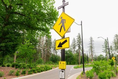 Orman bölgesindeki yerel bir yolda ikonik sarı yaya yolu tabelası. Yayaların refahını sağlamak, daha güvenli ve kapsayıcı bir ulaşım ortamı sağlamak..