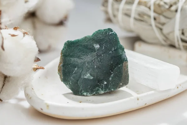 浅色背景下陶瓷盘上未切割的绿色苔藓Agate宝石 图库照片