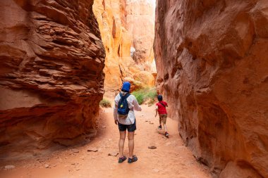 Bir kadın ve bir çocuk Dar Kum Taşı Çöl Kanyonu 'nda yürüyorlar. Ateşli fırında, Arches Ulusal Parkı, Utah, ABD