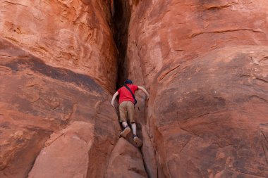 Genç Yürüyüşçü Amerika Birleşik Devletleri 'nin Utah eyaletindeki Arches Ulusal Parkı' nda Kum Taşı oluşumunda bir kayaya tırmanıyor..