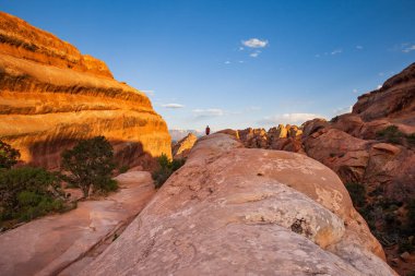Utah, Arches Ulusal Parkı 'ndaki Devils Garden Trail' in tepesinde bir yürüyüşçü duruyor.