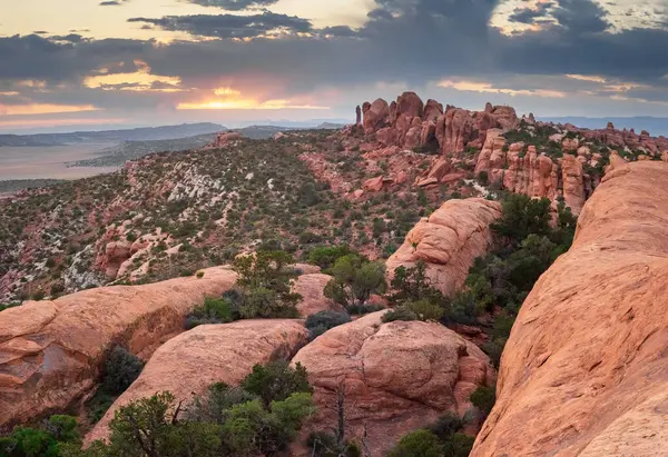 Utah, Arches Ulusal Parkı 'ndaki Devils Garden Trail' den çarpıcı bir günbatımı manzarası. Engebeli kızıl kaya oluşumları ve geniş çöl manzaraları batan güneşin sıcacık parıltısıyla aydınlanır..