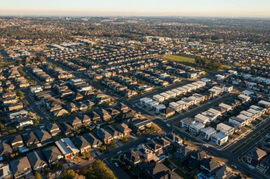 Late afternoon, wide aerial view of streets and similar sized modern Australian brick veneer homes in Sydney's rapidly growing and increasingly sprawling outer suburbs. clipart