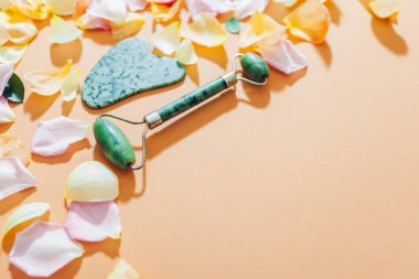Gül yapraklı yüz masajı için yeşim taşı seti ve gua sha taşı. Güzellik ve cilt bakımı masaj aleti. Model-up. Yaşlanma önleyici alet. Üst görünüm düzlüğü.