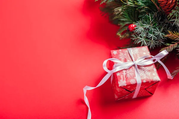 クリスマスと新年のギフトボックスは モミの庭でお祝いの赤い紙とリボンで包まれています 赤を背景に冬の休日のために存在します 宇宙モックアップ — ストック写真