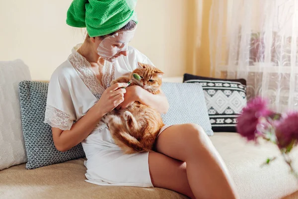 猫と一緒に風呂に入った後 自宅で玉ローラー美容ツールを使用して適用顔シートマスクを持つ女性 スキンケアルーチン ペットと遊ぶのは — ストック写真