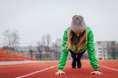 Spor giyim sektöründe genç bir kadın ya kalas yapıyor ya da kış sporları sahasında barfiks çekiyor. Antrenman yolunda. Sağlıklı yaşam tarzı için egzersiz. Boşluk