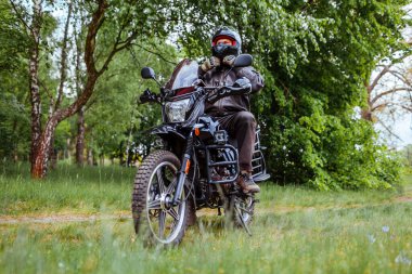 Motorcu yaz ormanlarında motosiklet sürdükten sonra kaskını çözer. Deri elbiseli bir adam. Sürücü nakliye aracında oturuyor. Yaz gezisi