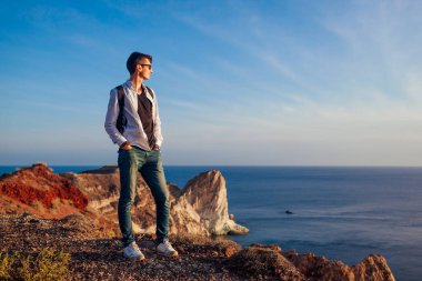 Santorini Adası 'ndaki White Beach' te yürüyen yürüyüşçü Yunanistan 'ın deniz manzarasının tadını çıkarıyor. Sırt çantalı bir adam seyahat ediyor. Yaz tatili