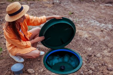 Otonom kanalizasyon sistemini kontrol eden bir kadın plastik septik kapağını kaldırıyor. Biyolojik atık su kanalizasyonu yeraltı tankı