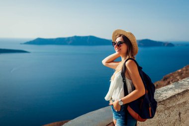 Santorini, Fira 'da Caldera deniz manzarasının tadını çıkaran kadın turist Ege deniz manzarasına bakıyor. Yaz tatili boyunca seyahat