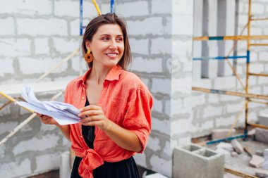 Mutlu genç bir kadının portresi inşaat projesinin planları altında evini kontrol ediyor. Müstakbel sahibi, gaz bloğundan yapılmış duvarın yanında rahat bir ev hayal ediyor.