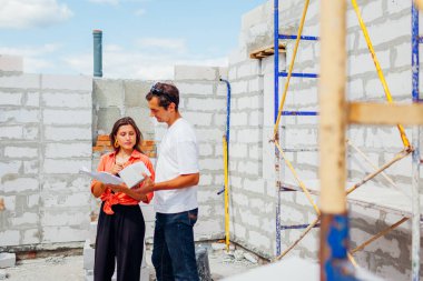Erkek mimar mühendis, müstakbel ev sahibine ev inşaatı için gaz bloğu malzemesi gösteriyor. İlerleme gösteren danışman istemci