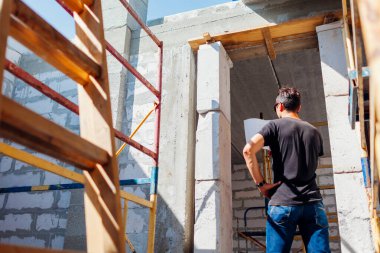 İnşaat halindeki evi kontrol eden mimar adamın arka planı kağıt üzerindeki planla karşılaştırılıyor. Gaz bloklu proje oluşturma