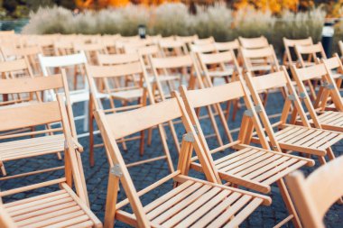 Konferanstan ya da düğün töreninden sonra boş tahta sandalyeler dışarıda bırakılmış. İş toplantısı bitti. Olaydan sonra parkta kimse kalmadı. Arkaplan