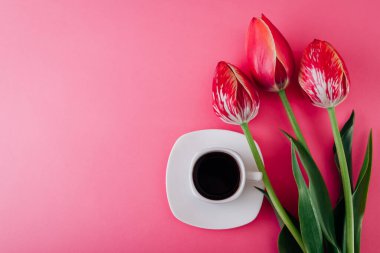 Sevgililer günü sabah kahvesi ve pembe arka planda bir buket taze lale çiçeği. Aşkı kutlamak için bayram hediyesi ve özen. Uzayı kopyala Üst görünüm