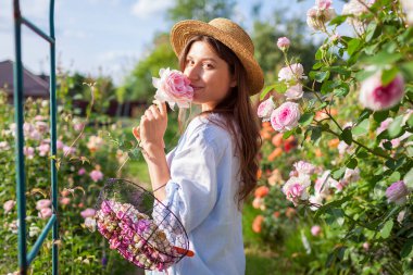 Bahçıvan portresi kokulu gül kokulu yaz bahçesinde bitkisel hayat harcadıktan sonra. Kadının elinde solmuş çiçekler ve budanmış budanmış budama sepetleri var..
