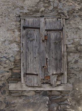 Ahşap kepenkler çok eski bir taş duvarın eski bir penceresini kapatıyor.