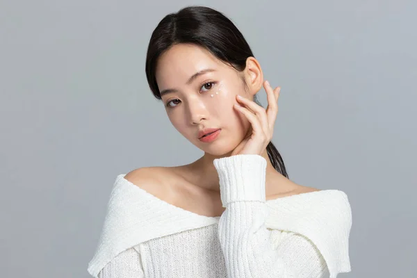 美しい若い韓国人女性のポートレートスタジオ写真で冬の肌の美しさと化粧品のコンセプト_使用アイクリーム — ストック写真
