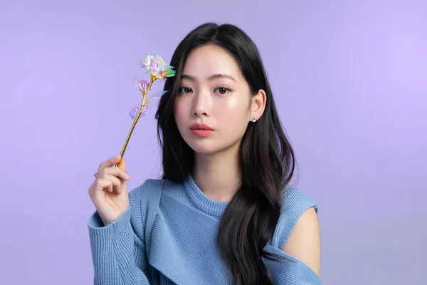 beautiful young Korean Asian woman portrait studio photo in winter skin beauty and cosmetics concept, holding a flower