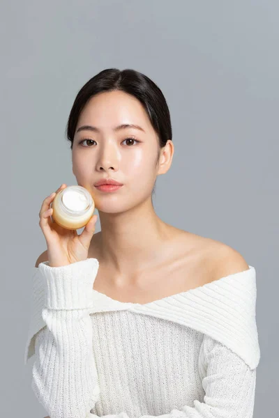 美丽的年轻的韩国亚洲女子肖像工作室照片在冬季皮肤美感和化妆品的概念 持有营养霜 — 图库照片