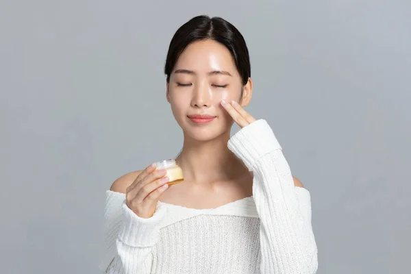 美丽的年轻的韩国亚洲女子肖像工作室照片在冬季皮肤美感和化妆品的概念 持有营养霜 — 图库照片