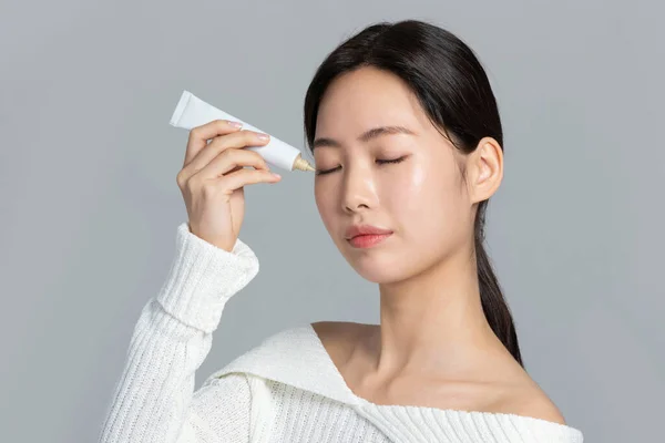 美丽的年轻的韩国亚洲女子肖像工作室照片冬季皮肤美感与化妆品概念 涂上眼霜 — 图库照片