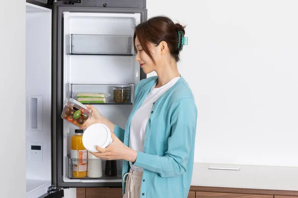 stock image happy single life of korean woman, look inside the fridge