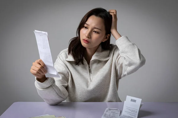 压力大 情绪低落的身穿粉红西服的韩国女商人一边看着账单一边思考着 — 图库照片