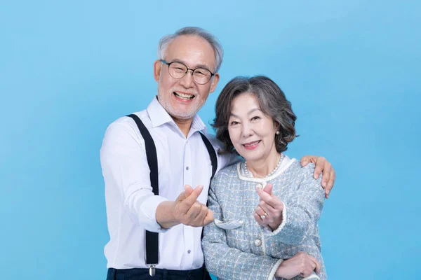 active young senior Korean Asian couple with hand motion against studio background