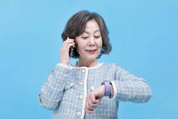 スマートウォッチデバイスを呼び出すアクティブ若いシニア韓国人女性 — ストック写真