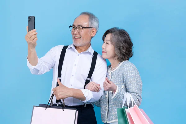 Active Young Senior Korean Asian Couple Holding Shopping Bags Smartphone — Stock Photo, Image