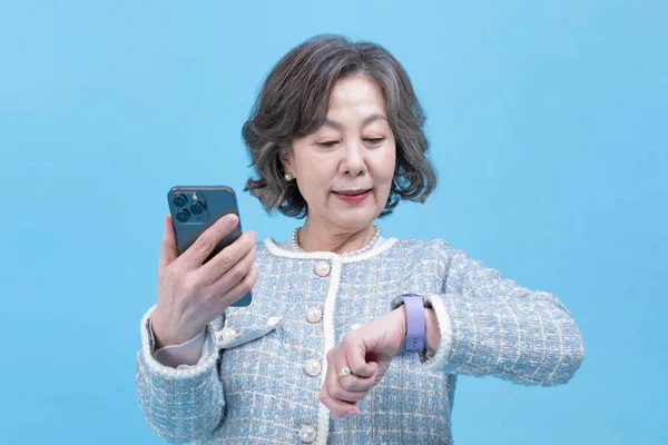 stock image active young senior Korean Asian woman on call with smart watch device