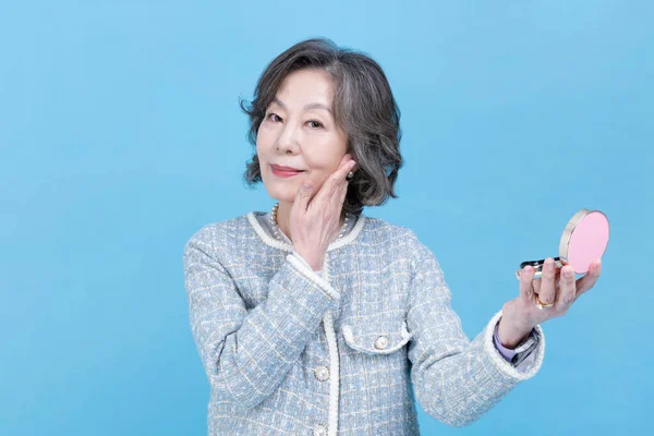持有美容化妆品的活跃的资深韩裔亚洲妇女 — 图库照片