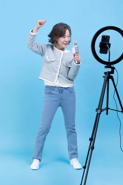 用智能手机 移动卡拉Ok的概念演唱活跃的资深韩裔亚洲女人 — 图库照片