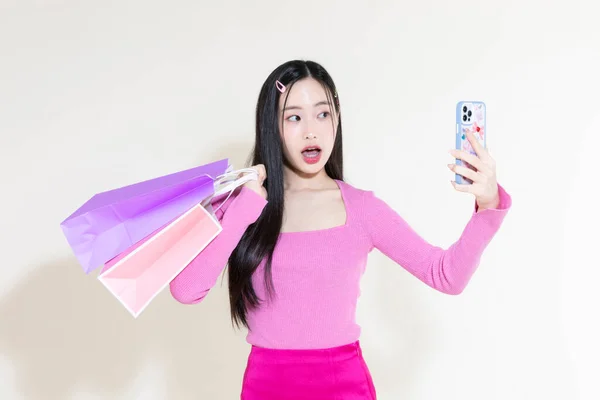 ヴィンテージY2Kピンクレトロなコンセプト写真韓国人可愛いアジア人女性がスマホやショッピングバッグを持っている — ストック写真