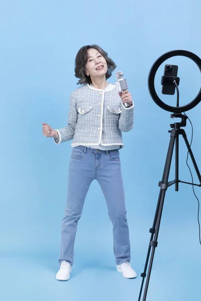 用智能手机 移动卡拉Ok的概念演唱活跃的资深韩裔亚洲女人 — 图库照片