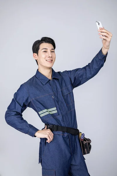 ミレニアル世代と韓国系アジア人の若い男性サイトスタッフがスマートフォンで自画自賛 — ストック写真