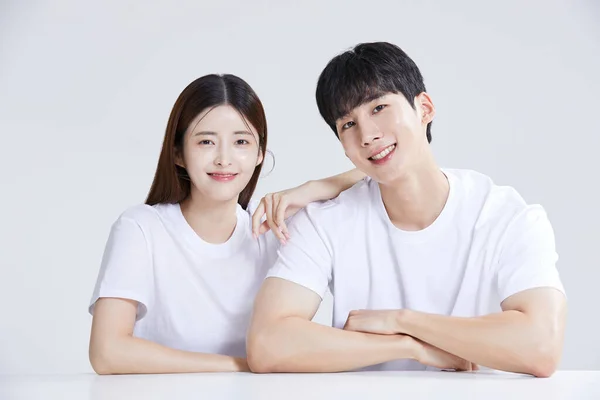 stock image korean asian young couple sitting with hands on shoulders, studio background