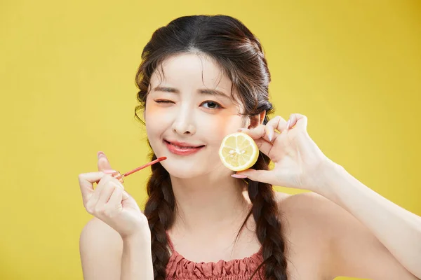 韩国美丽女人拿着唇膏和柠檬的美感照片 — 图库照片
