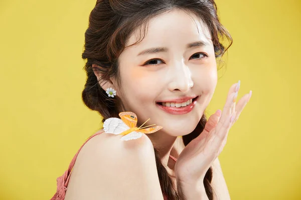 beauty concept photo of korean asain beautiful woman with a butterfly on her shoulder, smiling, studio background