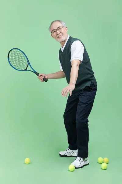 A senior man who plays tennis with a tennis racket