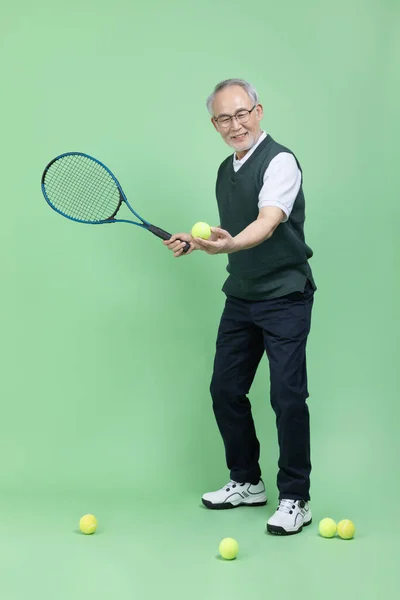 一个拿着网球拍和网球的高年级男生 — 图库照片